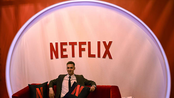 A man poses for a photo near a Netflix logo at their stall...