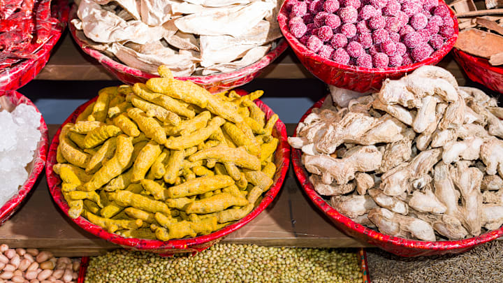 Turmeric, ginger, caraway seeds and peanuts are displayed in...