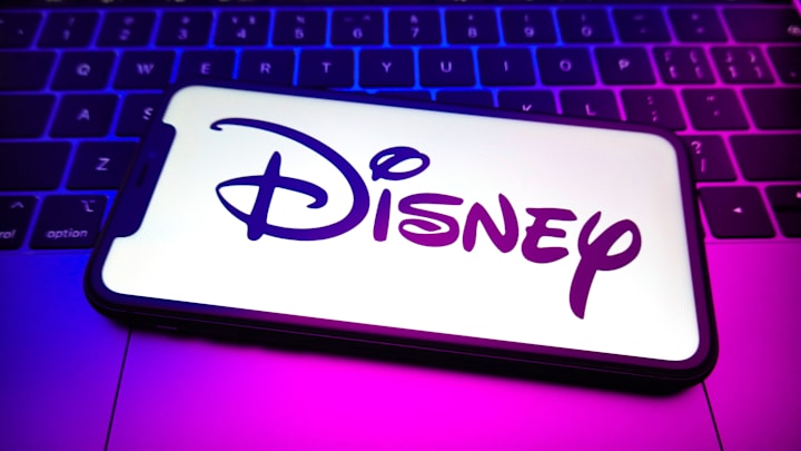 In this photo illustration, a Disney logo is displayed on...