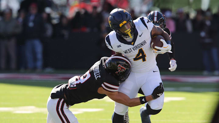 Nov 30, 2024; Lubbock, Texas, USA;  Texas Tech Red Raiders defensive back CJ Baskerville (9) tackles West Virginia Mountaineers running back CJ Donaldson Jr. (4) in the first half at Jones AT&T Stadium and Cody Campbell Field. Mandatory Credit: Michael C. Johnson-Imagn Images