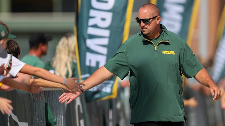 Green Bay Packers offensive coordinator Adam Stenavich slaps hands with fans as he walks to practice at training camp.