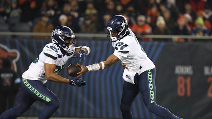 Dec 26, 2024; Chicago, Illinois, USA; Seattle Seahawks quarterback Geno Smith (7) hands the ball off to running back Kenny McIntosh (25) during the first quarter against the Chicago Bears at Soldier Field. Mandatory Credit: Talia Sprague-Imagn Images