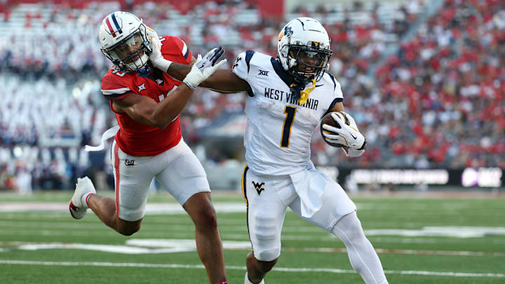 WVU football running back Jahiem White stiff arms a would-be tackler against Arizona during the 2024 football season.