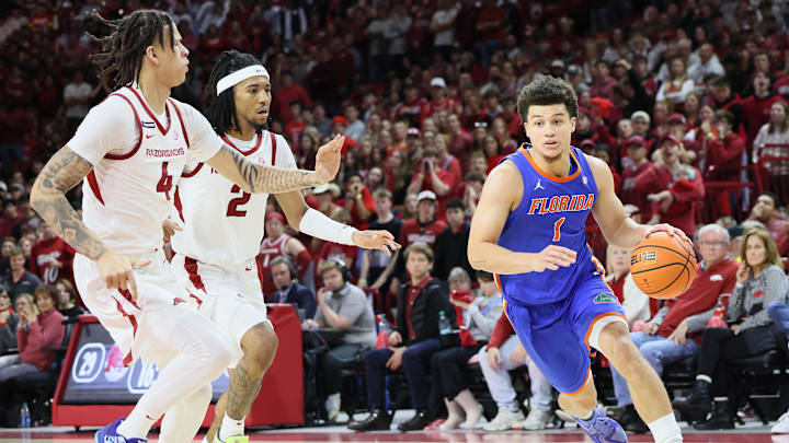Jan 11, 2025; Fayetteville, Arkansas, USA; Florida Gators guard Walter Clayton (1) dribbles around Arkansas Razorbacks forward Trevon Brazile (4) and guard Boogie Fland (2) during the second half at Bud Walton Arena. Mandatory Credit: Nelson Chenault-Imagn Images