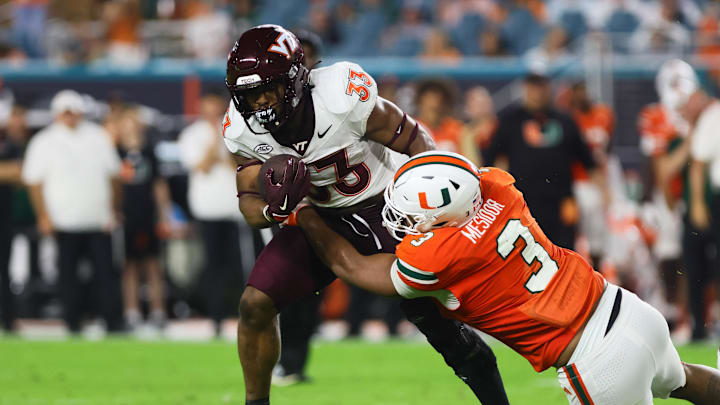 Sep 27, 2024; Miami Gardens, Florida, USA; Virginia Tech Hokies running back Bhayshul Tuten (33) runs with the football as Miami Hurricanes defensive lineman Akheem Mesidor (3) attempts a tackle during the second quarter at Hard Rock Stadium. Mandatory Credit: Sam Navarro-Imagn Images