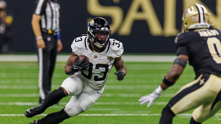 Aug 17, 2025; New Orleans, Louisiana, USA;  Jacksonville Jaguars running back Bhayshul Tuten (33) runs against New Orleans Saints safety Ugo Amadi (0) during the first half at Caesars Superdome. Mandatory Credit: Stephen Lew-Imagn Images