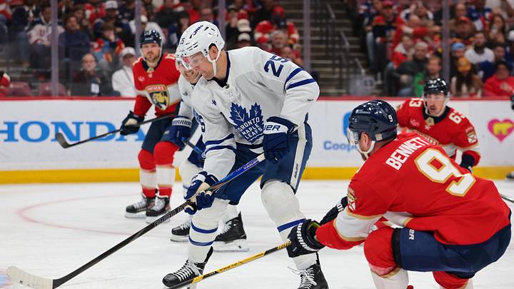 Feb 26, 2026; Sunrise, Florida, USA; Toronto Maple Leafs defenseman Brandon Carlo (25) moves the puck against Florida Panthers center Sam Bennett (9) during the first period at Amerant Bank Arena. Mandatory Credit: Sam Navarro-Imagn Images