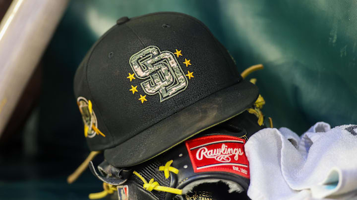 A detailed view of a San Diego Padres hat and glove on the bench against the Atlanta Braves in the third inning at Truist Park in 2024.