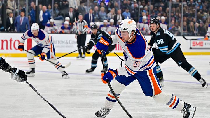 Oct 17, 2026; Salt Lake City, Utah, USA;  Edmonton Oilers left wing Isaac Howard (53) takes a shot on goal around Utah Mammoth defenseman MacKenzie Weegar (52) during first period at Delta Center.  Mandatory Credit: Peter Creveling-Imagn Images