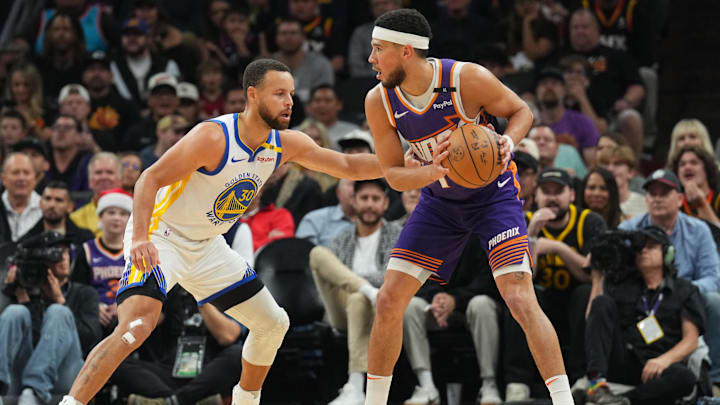 Nov 30, 2024; Phoenix, Arizona, USA; Golden State Warriors guard Stephen Curry (30) guards Phoenix Suns guard Devin Booker (1) during the first half at Footprint Center. 