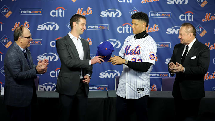 Dec 12, 2024; Flushing, NY, USA; New York Mets general manager David Stearns hands a cap to New York Mets right fielder Juan Soto (22) during Soto's introductory press conference at Citi Field. Also pictured New York Mets owner Steve Cohen (left) and agent Scott Boras (right). Mandatory Credit: Brad Penner-Imagn Images