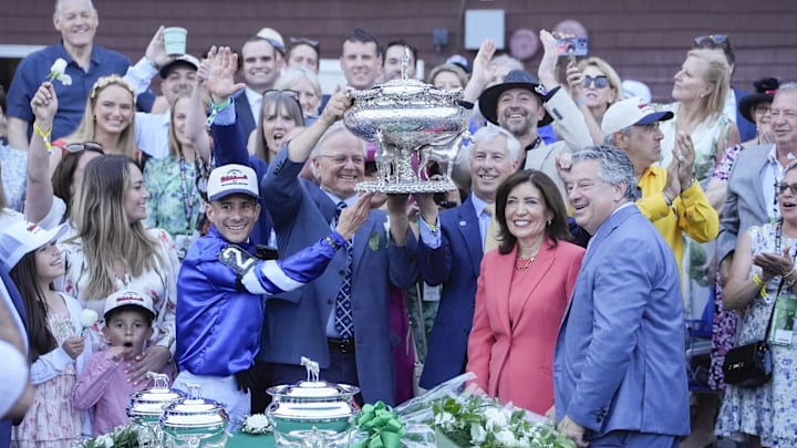 Junior Alvarado and trainer Bill Mott and a representative from the ownership group of Godolphin hold up the Belmont Stakes trophy. Sovereignty makes his return Saturday in the Grade 2 Jim Dandy Stakes.
