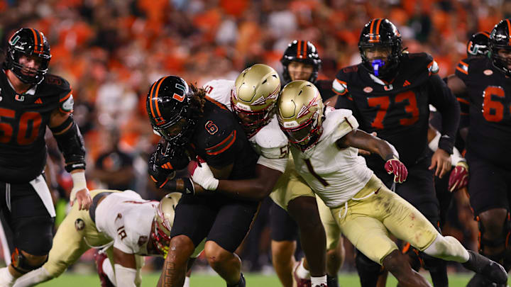 Oct 26, 2024; Miami Gardens, Florida, USA; Miami Hurricanes running back Damien Martinez (6) runs with the football against Florida State Seminoles defensive lineman KJ Sampson (56) and defensive back Shyheim Brown (1) during the fourth quarter at Hard Rock Stadium. Mandatory Credit: Sam Navarro-Imagn Images