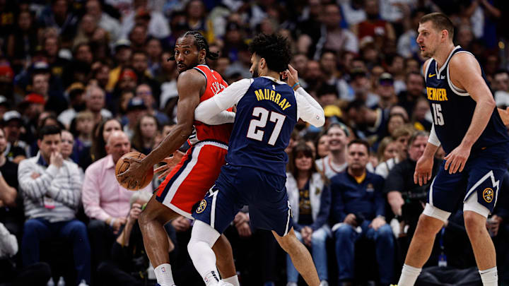 Apr 21, 2025; Denver, Colorado, USA; Los Angeles Clippers forward Kawhi Leonard (2) controls the ball as Denver Nuggets guard Jamal Murray (27) guards and center Nikola Jokic (15) defends in the third quarter during game two of first round for the 2025 NBA Playoffs at Ball Arena. Mandatory Credit: Isaiah J. Downing-Imagn Images