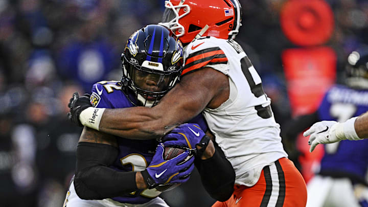 Baltimore Ravens quarterback Lamar Jackson controls the ball as Cleveland Browns defensive end Myles Garrett defends.