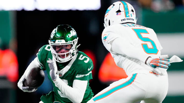 New York Jets wide receiver Garrett Wilson (5) runs with the ball as he tries to find a way past Miami Dolphins cornerback Jalen Ramsey (5), Sunday January 5, 2025, in East Rutherford.