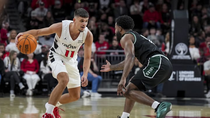 Nov 26, 2025; Cincinnati, Ohio, USA;  Cincinnati Bearcats guard Kerr Kriisa (11) dribbles the ball against Eastern Michigan Eagles guard Jon Sanders (10) in the first half at Fifth Third Arena. Mandatory Credit: Aaron Doster-Imagn Images