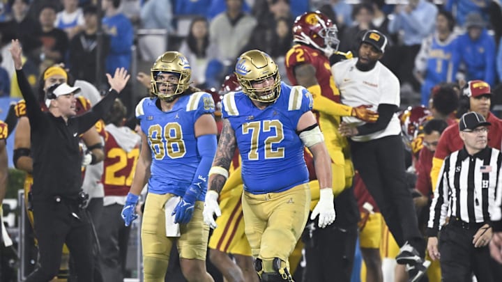 Nov 23, 2024; Pasadena, California, USA; UCLA Bruins tight end Moliki Matavao (88) and UCLA Bruins offensive lineman Garrett DiGiorgio (72) walks off the field USC Trojans head coach Lincoln Riley (far left) and bench celebrates in the closing minute at Rose Bowl. Mandatory Credit: Robert Hanashiro-Imagn Images