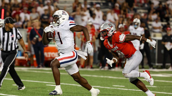 Aug 31, 2024; Tucson, Arizona, USA; Arizona Wildcats running back Jacory Croskey-Merritt (1) runs the ball for a touchdown while New Mexico Lobos safety Christian Ellis (8) chases him during fourth quarter at Arizona Stadium. Mandatory Credit: Aryanna Frank-Imagn Images
