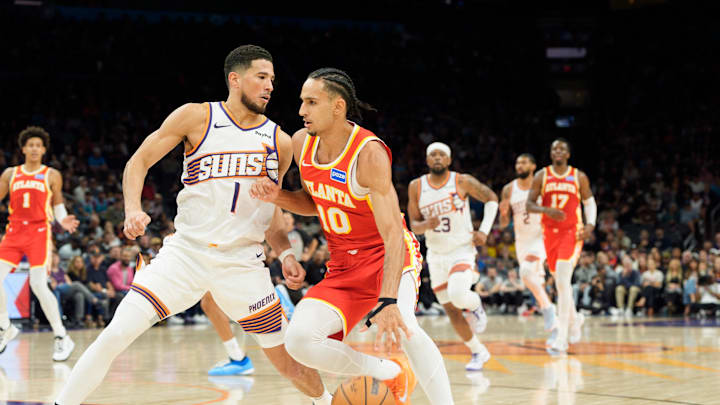 Nov 16, 2025; Phoenix, Arizona, USA; Atlanta Hawks forward Zaccharie Risacher (10) and drives as Phoenix Suns guard Devin Booker (1) defends during the second half of play during a game at Mortgage Matchup Center. Mandatory Credit: Allan Henry-Imagn Images