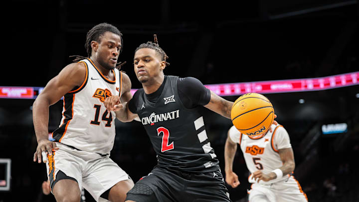 Mar 11, 2025; Kansas City, MO, USA; Cincinnati Bearcats guard Jizzle James (2) drives to the basket around Oklahoma State Cowboys guard Jamyron Keller (14) during the second half at T-Mobile Center. Mandatory Credit: William Purnell-Imagn Images