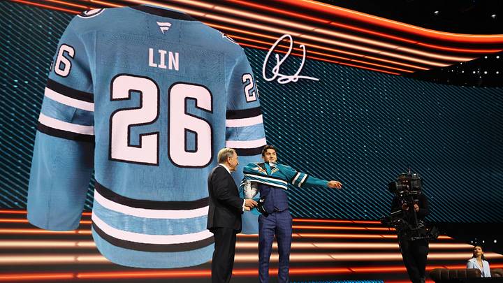 Jun 26, 2026; Buffalo, New York, USA; Ryan Lin reacts beside NHL commissioner Gary Bettman after being selected with the twenty first pick in the first round of the 2026 NHL Draft by the San Jose Sharks at KeyBank Center. Mandatory Credit: Timothy T. Ludwig-Imagn Images