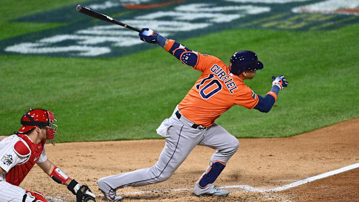 Houston Astros first baseman Yuli Gurriel swings the bat wearing an orange jersey and navy blue hat.