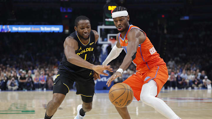 Nov 11, 2025; Oklahoma City, Oklahoma, USA; Golden State Warriors forward Jonathan Kuminga (1) and Oklahoma City Thunder guard Shai Gilgeous-Alexander (2) reach for a loose ball during the second half at Paycom Center. Mandatory Credit: Alonzo Adams-Imagn Images