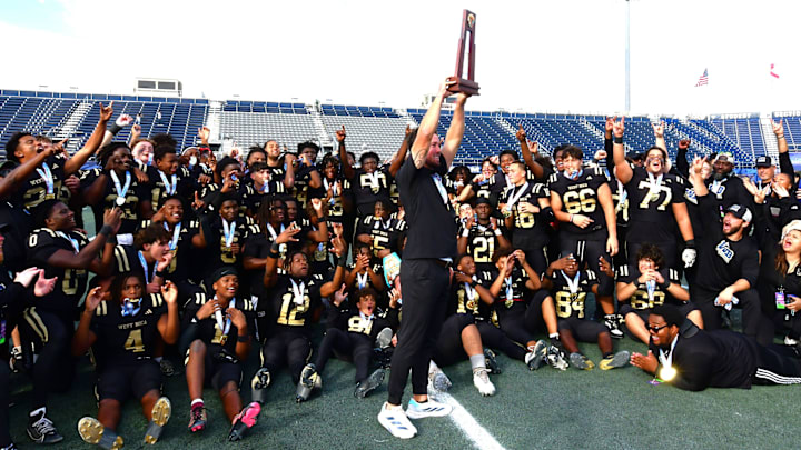 West Boca head coach Dylan Potts holds the trophy high after a Class 6A State Championship win against Osceola on Dec. 13, 2024.