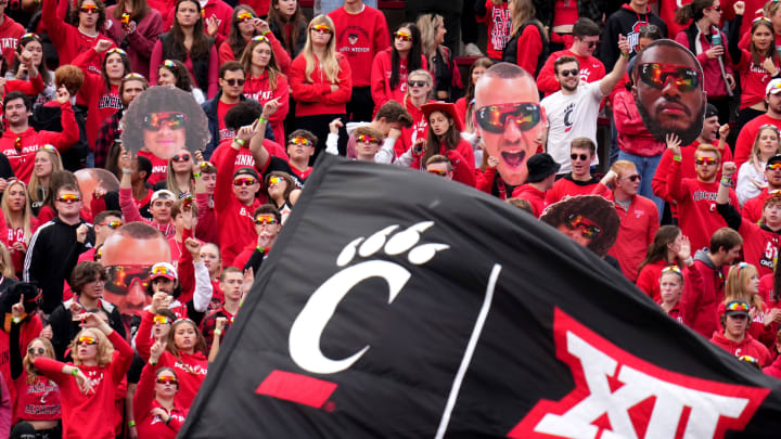The Cincinnati Bearcats student section cheers on the team as a flag with the C-paw and Big 12 Conference logos is waved after a touchdown in the second quarter during a college football game between the Baylor Bears and the Cincinnati Bearcats, Saturday, Oct. 21, 2023, at Nippert Stadium in Cincinnati.