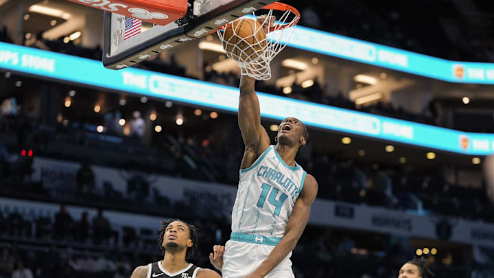Jan 29, 2025; Charlotte, North Carolina, USA; Charlotte Hornets forward Moussa Diabate (14) gets a dunk past Brooklyn Nets center Nic Claxton (33) during the second half at Spectrum Center. Mandatory Credit: Jim Dedmon-Imagn Images