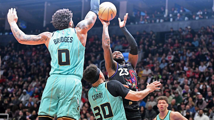 Mar 28, 2025; Toronto, Ontario, CAN;  Toronto Raptors guard Jamal Shead (23) shoots the ball over Charlotte Hornets guard Seth Curry (30) and forward Miles Bridges (0) in the first half at Scotiabank Arena. Mandatory Credit: Dan Hamilton-Imagn Images