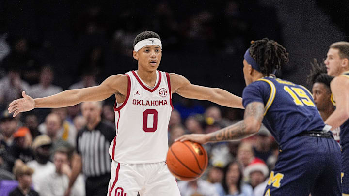 Dec 18, 2024; Charlotte, North Carolina, USA; Oklahoma Sooners guard Jeremiah Fears (0) on defense against Michigan Wolverines guard Rubin Jones (15) during the first half at Spectrum Center. Mandatory Credit: Jim Dedmon-Imagn Images