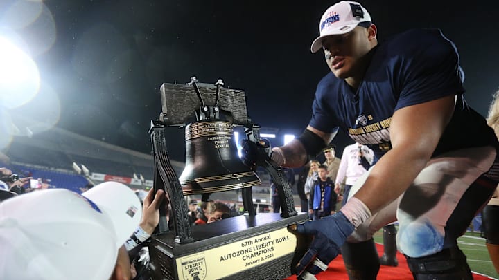 Jan 2, 2026; Memphis, TN, USA; Navy Midshipmen defensive lineman Landon Robinson (96) passes the Liberty Bell trophy off the stage after defeating the Cincinnati Bearcats in the Liberty Bowl at Simmons Bank Liberty Stadium. Mandatory Credit: Petre Thomas-Imagn Images