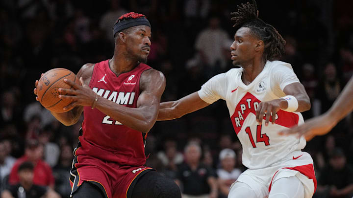 Nov 29, 2024; Miami, Florida, USA;  Miami Heat forward Jimmy Butler (22) looks to pass the ball as Toronto Raptors guard Ja'Kobe Walter (14) defends during the second half in an NBA Cup game at Kaseya Center. Mandatory Credit: Jim Rassol-Imagn Images