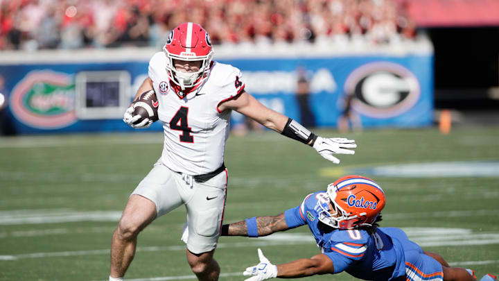 Nov 1, 2025; Jacksonville, Florida, USA; Georgia Bulldogs tight end Oscar Delp (4) evades Florida Gators defensive back Sharif Denson (0) in the first quarter at EverBank Stadium. Mandatory Credit: Travis Register-Imagn Images