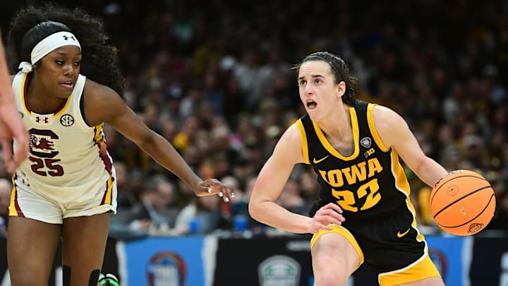 Iowa Hawkeyes guard Caitlin Clark (22) dribbles the ball past South Carolina Gamecocks guard Raven Johnson (25) 