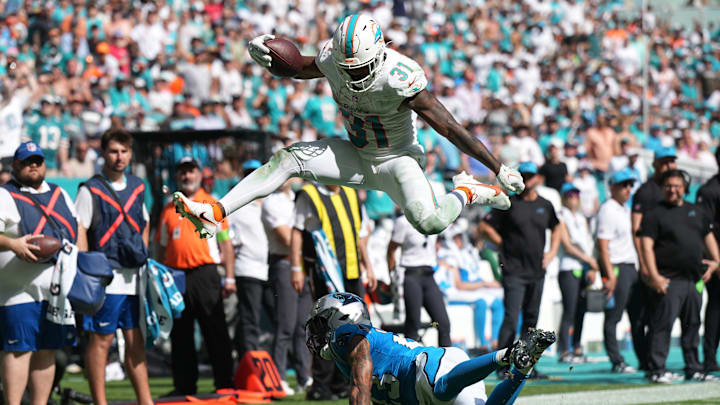 Miami Dolphins running back Raheem Mostert (31) hurdles over Carolina Panthers cornerback CJ Henderson (23) during the fourth quarter of an NFL game at Hard Rock Stadium in Miami Gardens, Oct. 15, 2023.