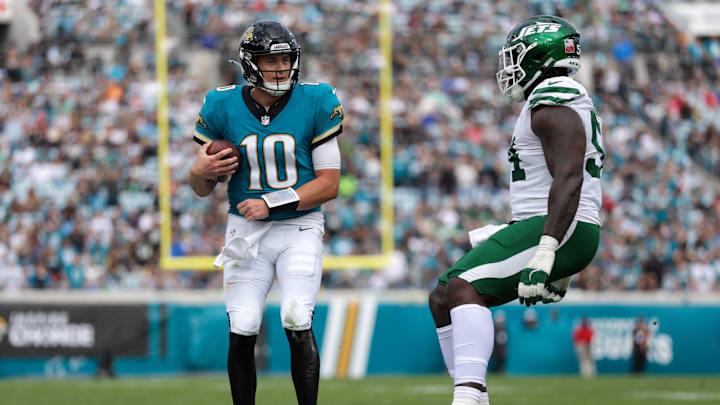 Dec 15, 2024; Jacksonville, Florida, USA; Jacksonville Jaguars quarterback Mac Jones (10) is forced out of bounds by New York Jets defensive tackle Javon Kinlaw (54) in the second quarter at EverBank Stadium. Mandatory Credit: Nathan Ray Seebeck-Imagn Images