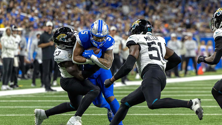 Nov 17, 2024; Detroit, Michigan, USA; Detroit Lions running back David Montgomery (5) runs with the ball and is tackles by Jacksonville Jaguars linebacker Foyesade Oluokun (23) and linebacker Ventrell Miller (51) during the first half at Ford Field. Mandatory Credit: David Reginek-Imagn Images