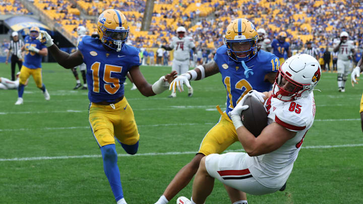 Sep 27, 2025; Pittsburgh, Pennsylvania, USA;  Louisville Cardinals tight end Nate Kurisky (85) catches a touchdown pass behind Pittsburgh Panthers defensive backs Rashad Battle (15) and Cruce Brookins (12) during the fourth quarter at Acrisure Stadium. Mandatory Credit: Charles LeClaire-Imagn Images