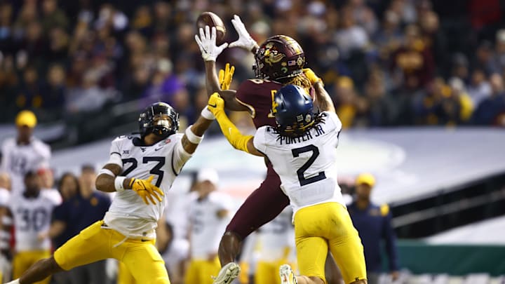 Dec 28, 2021; Phoenix, AZ, USA; Minnesota Golden Gophers wide receiver Dylan Wright (16) catches a pass against West Virginia Mountaineers cornerback Daryl Porter Jr. (2) and Charles Woods (23) in the first half of the Guaranteed Rate Bowl at Chase Field. Mandatory Credit: Mark J. Rebilas-Imagn Images