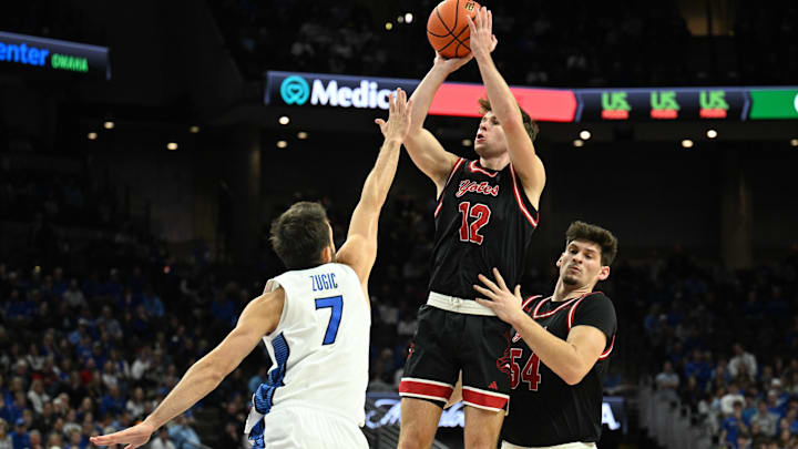 Nov 5, 2025; Omaha, Nebraska, USA;  South Dakota Coyotes guard Isaac Bruns (12) shoots over Creighton Bluejays guard Fedor Zugic (7) during the first half at CHI Health Center Omaha. Mandatory Credit: Steven Branscombe-Imagn Images