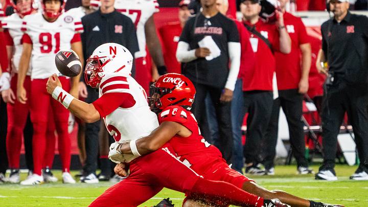 Aug 28, 2025; Kansas City, Missouri, USA; Nebraska Cornhuskers quarterback Dylan Raiola (15) fumbles against Cincinnati Bearcats linebacker Jonathan Thompson (22) during the second quarter at GEHA Field at Arrowhead Stadium. Mandatory Credit: Dylan Widger-Imagn Images
