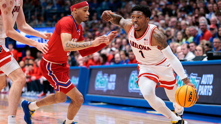 Mar 8, 2025; Lawrence, Kansas, USA; Arizona Wildcats guard Caleb Love (1) drives to the basket around Kansas Jayhawks guard Dajuan Harris Jr. (3) during the first half at Allen Fieldhouse. Mandatory Credit: William Purnell-Imagn Images