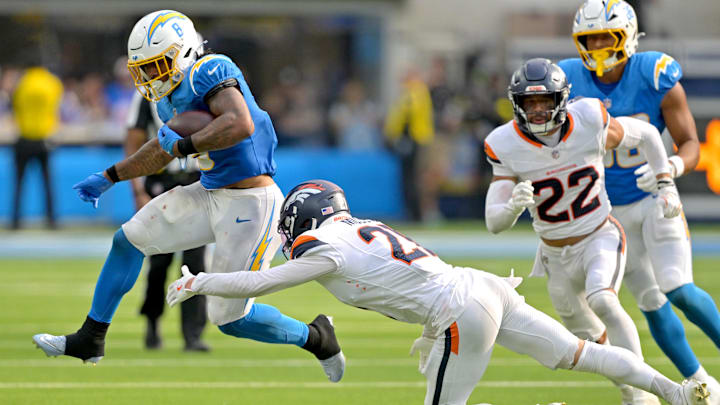 Chargers running back Omarion Hampton (8) is tripped up by the Broncos in Week 4.