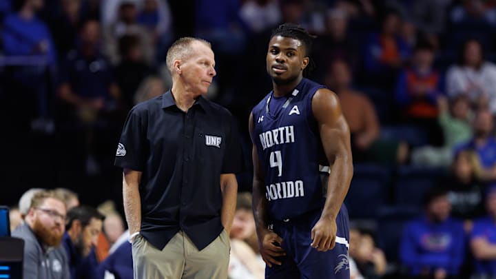 Dec 21, 2024; Gainesville, Florida, USA; North Florida Ospreys head coach Matthew Driscoll talks with North Florida Ospreys guard Jaylen Smith (4) during a free throw against the Florida Gators during the second half at Exactech Arena at the Stephen C. O'Connell Center. Mandatory Credit: Matt Pendleton-Imagn Images