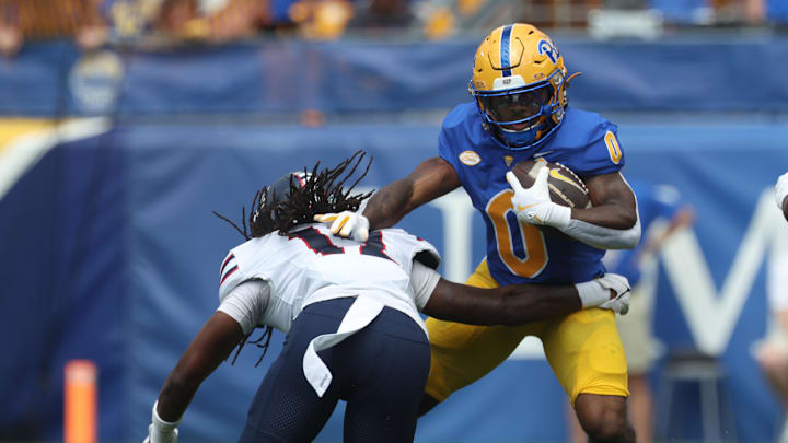 Aug 30, 2025; Pittsburgh, Pennsylvania, USA; Pittsburgh Panthers running back Desmond Reid (0) carries the ball against Duquesne Dukes defensive back Dallas Harper (12) during the first quarter at Acrisure Stadium. Mandatory Credit: Charles LeClaire-Imagn Images
