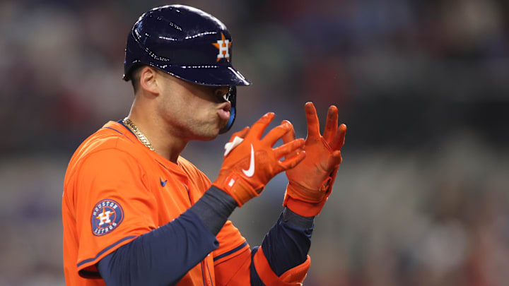 A baseball player in an orange and navy blue uniform, wearing orange gloves and a navy blue helmet.