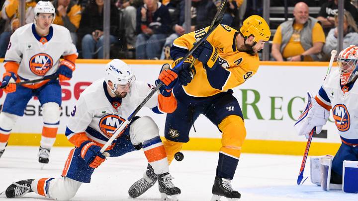 Jan 8, 2026; Nashville, Tennessee, USA; Nashville Predators center Ryan O'Reilly (90) and New York Islanders defenseman Adam Pelech (3) battle for the puck during the third period at Bridgestone Arena. Mandatory Credit: Steve Roberts-Imagn Images
